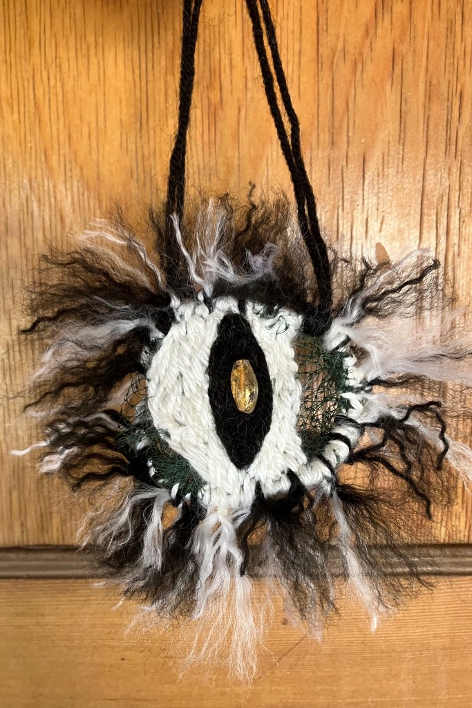 A hand-stitched eyeball with white and black yarn and a glass bead.