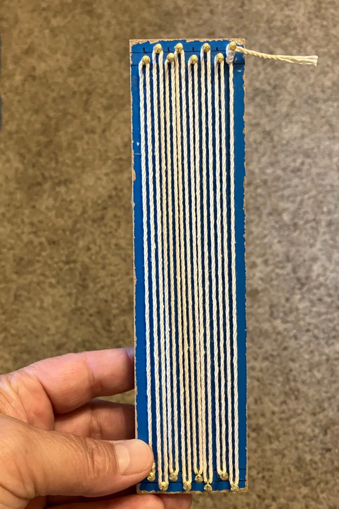 A mini loom (with warp strings) made by fiber artist, Sarah Batchelder.