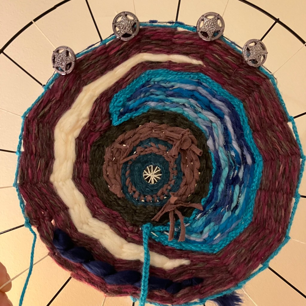 A close up of the current project by fiber artist Sarah Batchelder, shows a few crescent shapes in different colors and textures.