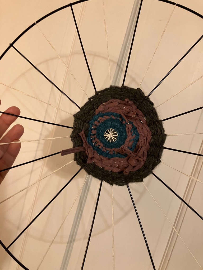 Progress made on the project by fiber artist, Sarah Batchelder, shows more fibers added to the center of the weaving.