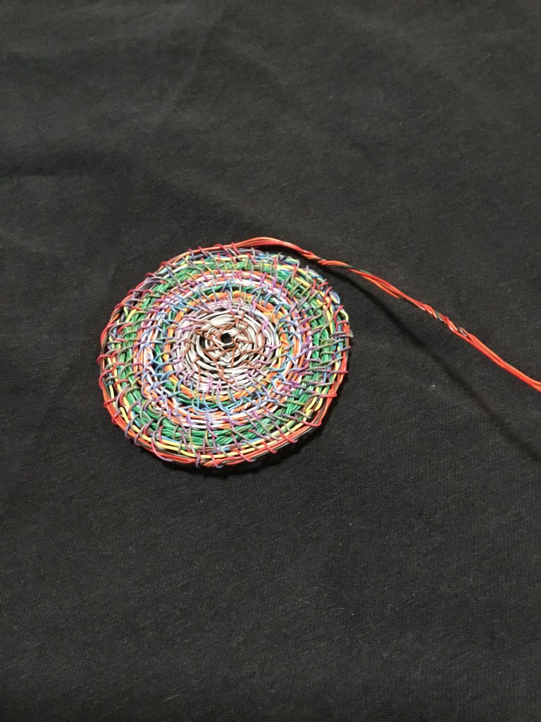 A flat round spiral wire weaving in multiple colors