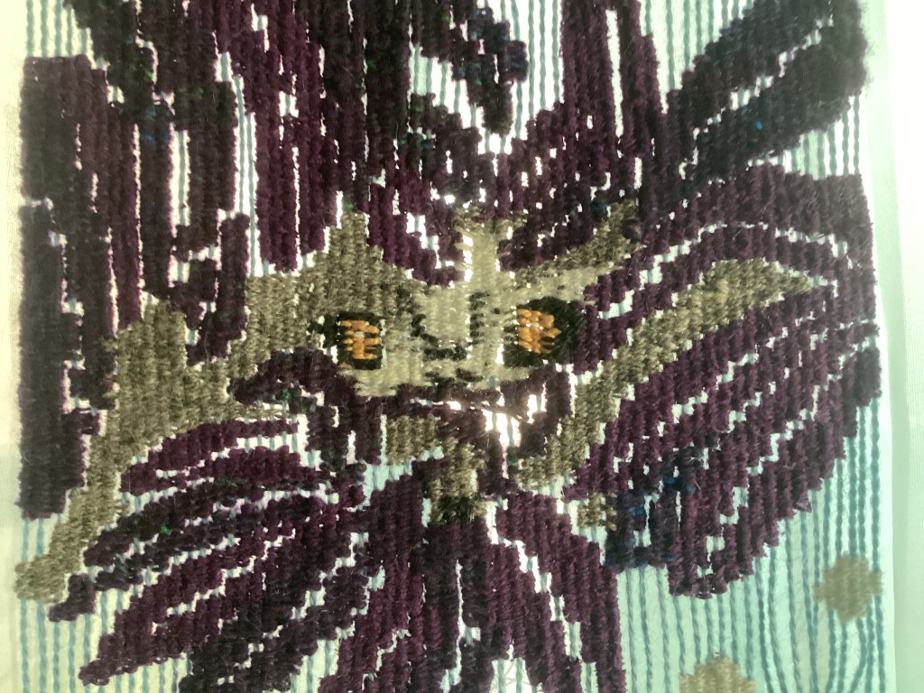A close up of wolf eyes from a tapestry woven by Sarah Batchelder.